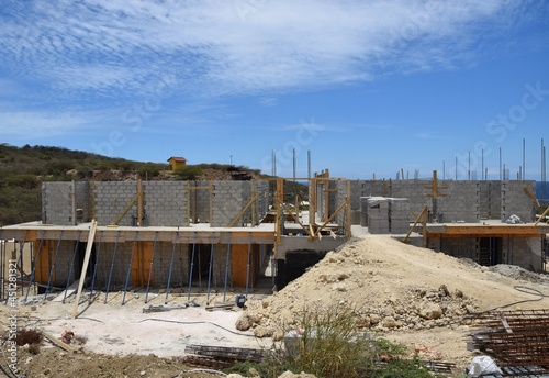 View of a building construction site with sand and block material, hillside and blue sky in the background © skyf