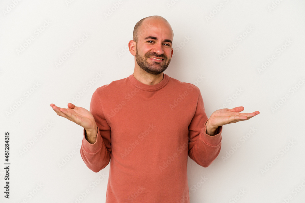 Young bald man isolated on white background makes scale with arms, feels happy and confident. Young bald man isolated on white background makes scale with arms, feels happy and confident.