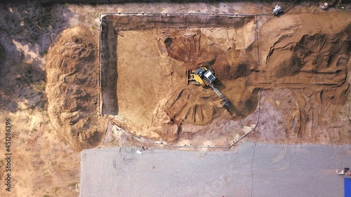Excavator on a construction site excavates a cellar. civil engineering, earthworks, excavation from a bird's eye view photo
