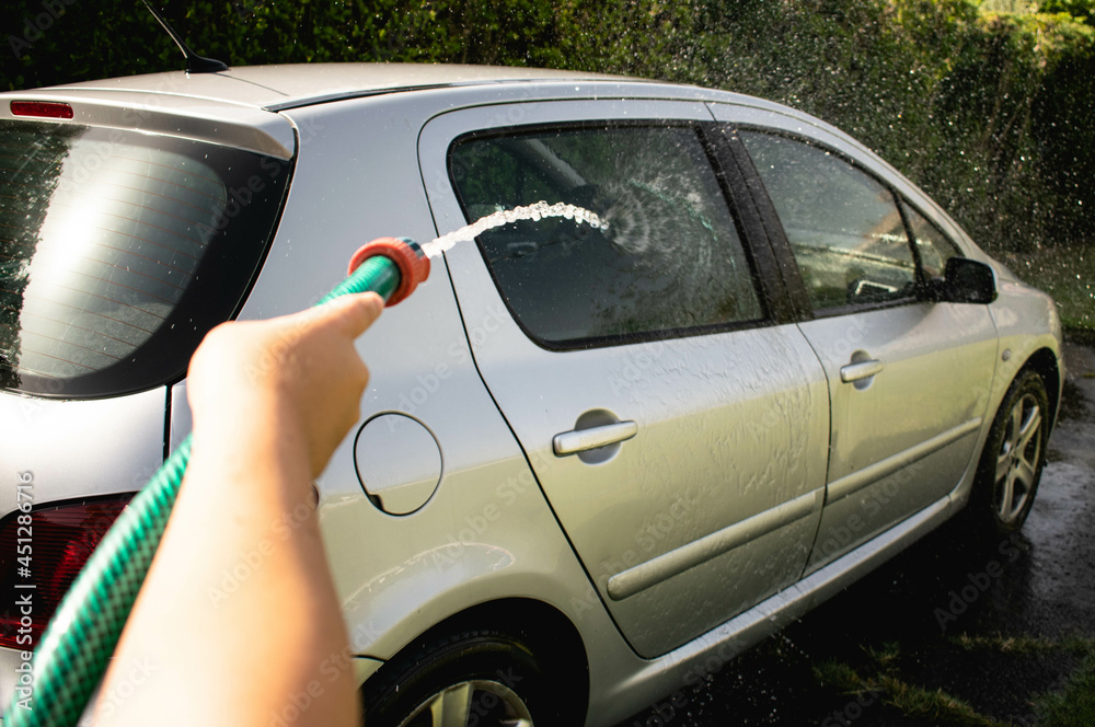 Man cleaning a car with a hose Man cleaning a car with a hose