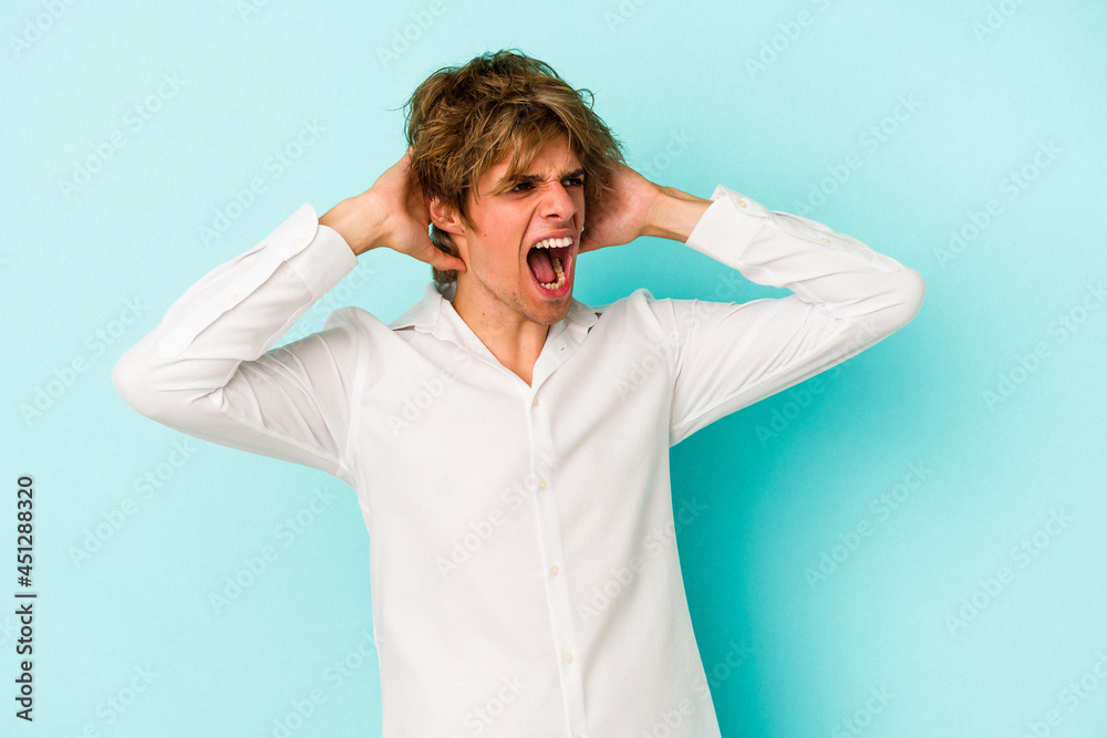 Young caucasian man with make up isolated on blue background screaming, very excited, passionate, satisfied with something. Young caucasian man with make up isolated on blue background screaming, very excited, passionate, satisfied with something.