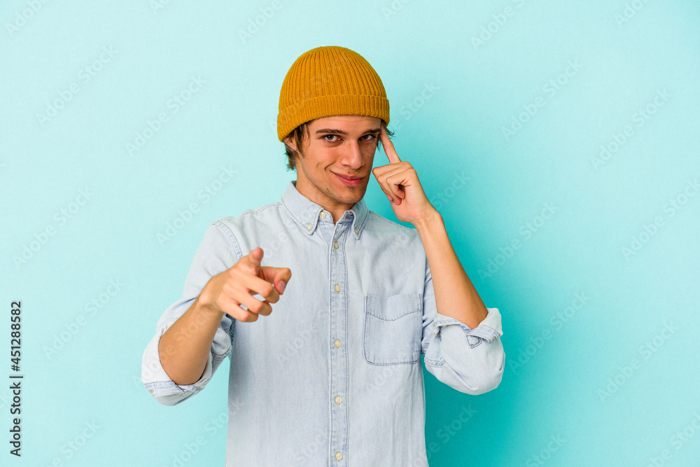 Young caucasian man with make up isolated on blue background  pointing temple with finger, thinking, focused on a task.