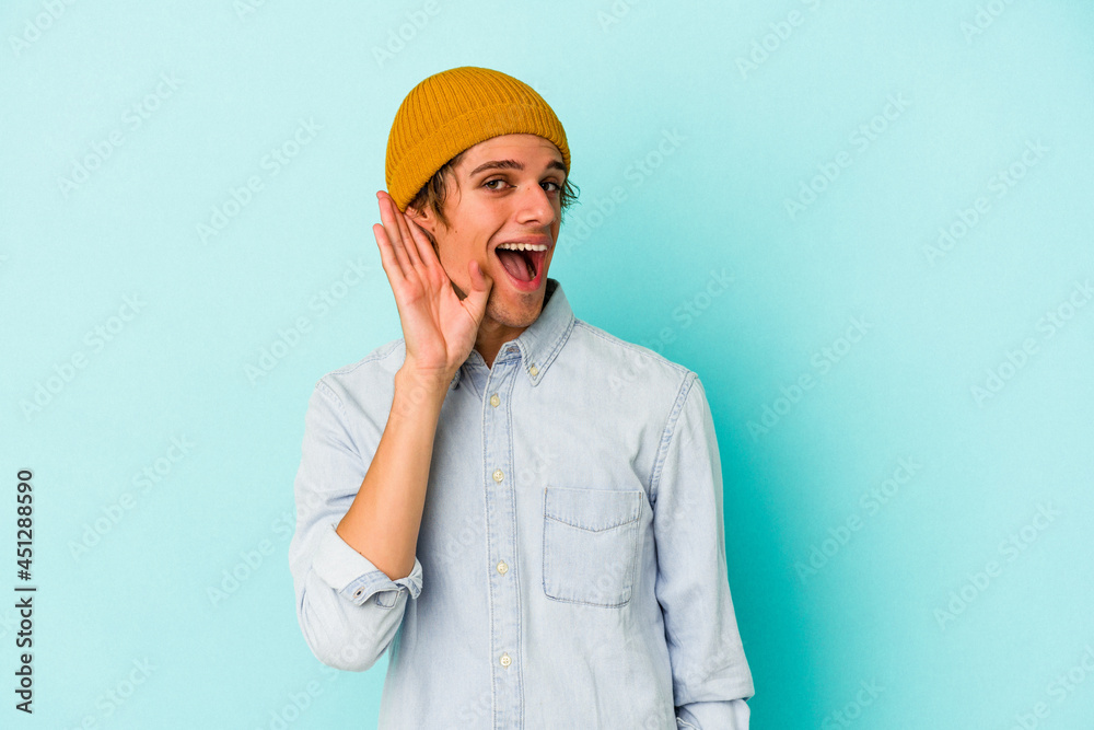Young caucasian man with make up isolated on blue background trying to listening a gossip. Young caucasian man with make up isolated on blue background trying to listening a gossip.