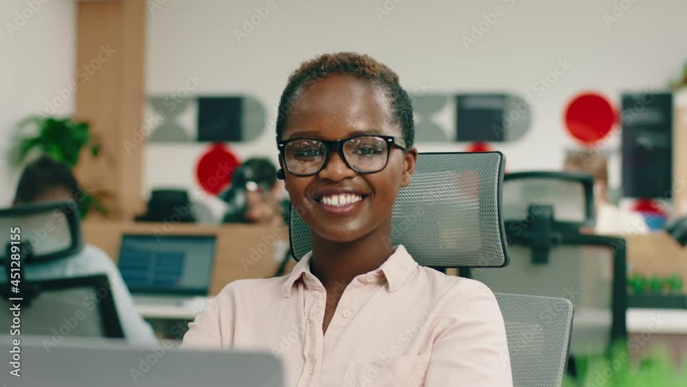A quick witted young black woman is looking directly at the camera, she is at her office looking very happy A quick witted young black woman is looking directly at the camera, she is at her office looking very happy