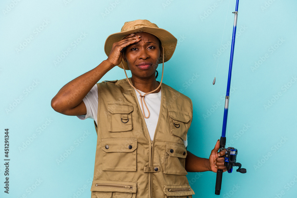 Young african american fisherwoman holding rod isolated on blue background being shocked, she has remembered important meeting. Young african american fisherwoman holding rod isolated on blue background being shocked, she has remembered important meeting.