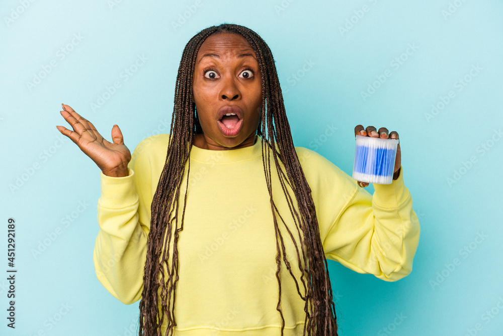 Young african american woman holding cotton bulls isolated on buds background surprised and shocked. - obrazy, fototapety, plakaty 