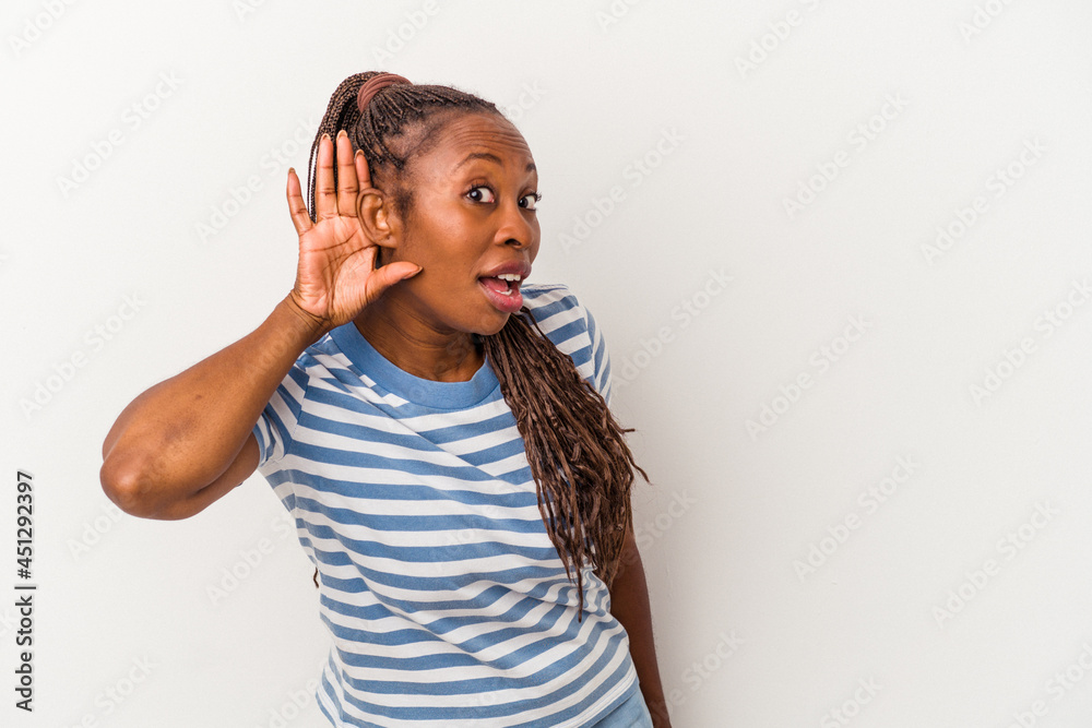 Young african american woman isolated on white background trying to listening a gossip. Young african american woman isolated on white background trying to listening a gossip.