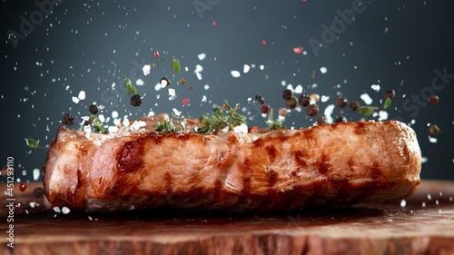 Super Slow Motion Shot of Falling Fresh Grilled Meat Steak and Seasoning on Wooden Board at 1000fps. photo