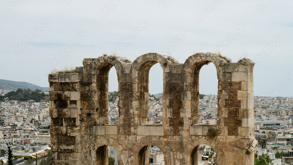 Close-up of remains of wall of The Odeon of Herodes Atticus in Athens. Cityscape of Athens at cloudy day. Acropolis hill.