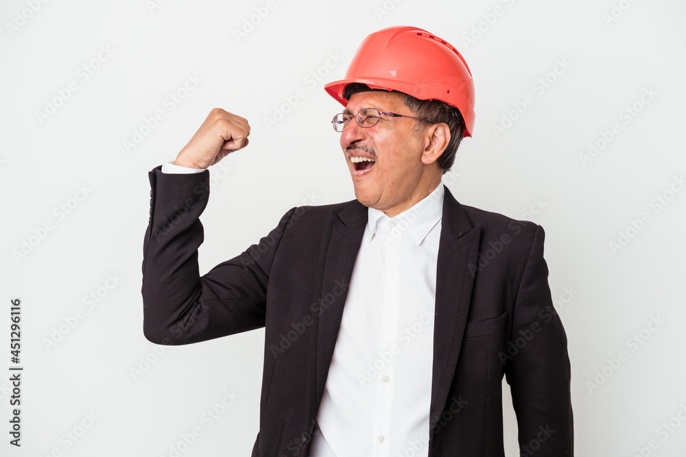 Middle aged indian architect man isolated on white background raising fist after a victory, winner concept.