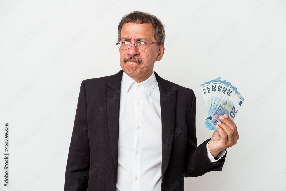 Middle aged indian business man holding bills isolated on white background confused, feels doubtful and unsure. Middle aged indian business man holding bills isolated on white background confused, feels doubtful and unsure.