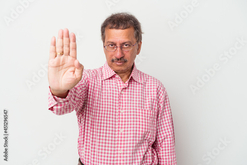 Middle aged indian man isolated on white background standing with outstretched hand showing stop sign, preventing you.