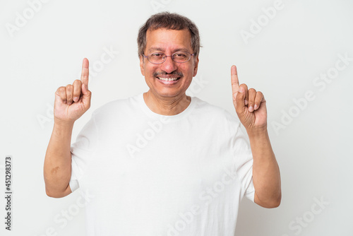 Middle aged indian man isolated on white background indicates with both fore fingers up showing a blank space.
