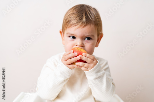 Toddler baby with apples on the high chair. Healthy eating. Summer and autumn harvest. Studio shot