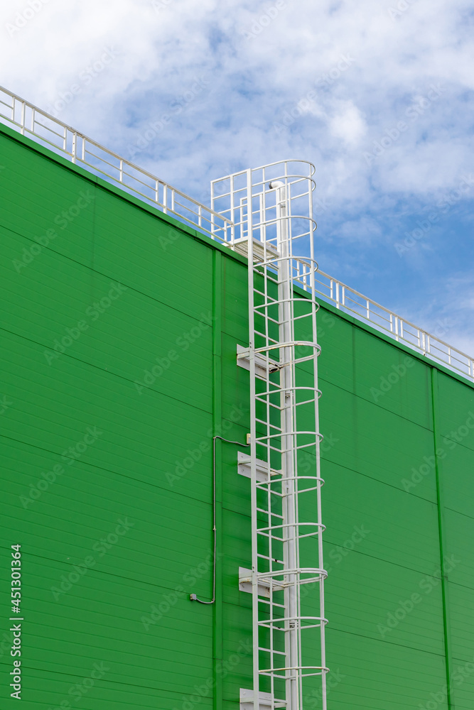 Fototapeta premium white metal fire escape on the green facade of an industrial building. Vertical
