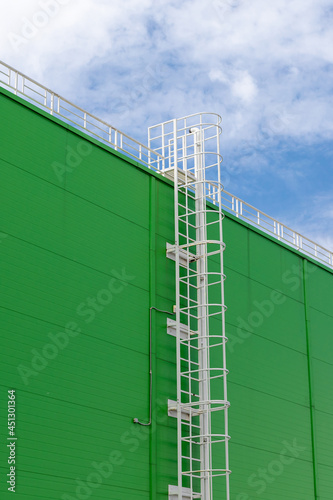 white metal fire escape on the green facade of an industrial building. Vertical