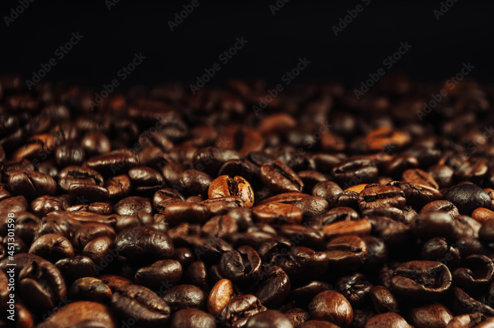 Fototapeta premium Coffee beans close up. The concept of making aromatic strong coffee on a black background in a low key. Discreet photography.
