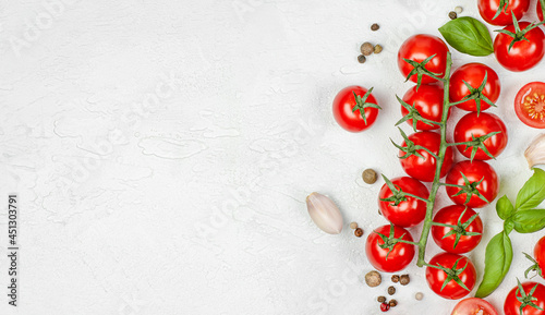 cherry tomatoes, basil, garlic and peppercorns on a light concrete background