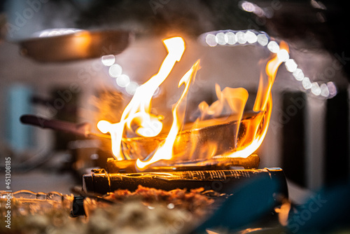 Copper pan engulfed in flames on cooking burner at outdoor resort buffet photo