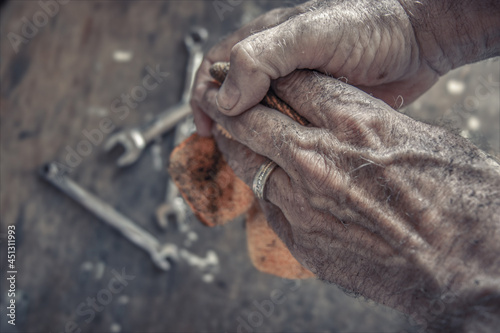 Fényképezés Closeup of a man wiping his dirty hands on an oily rag, wedding band on hand and