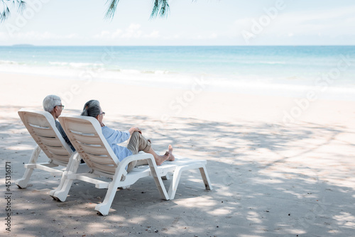 Retired couple resting on a adirondack chair by the beach in the sunlight and clean sandy beach. Retirement Planning Ideas and Happy Life. © nitinai2518