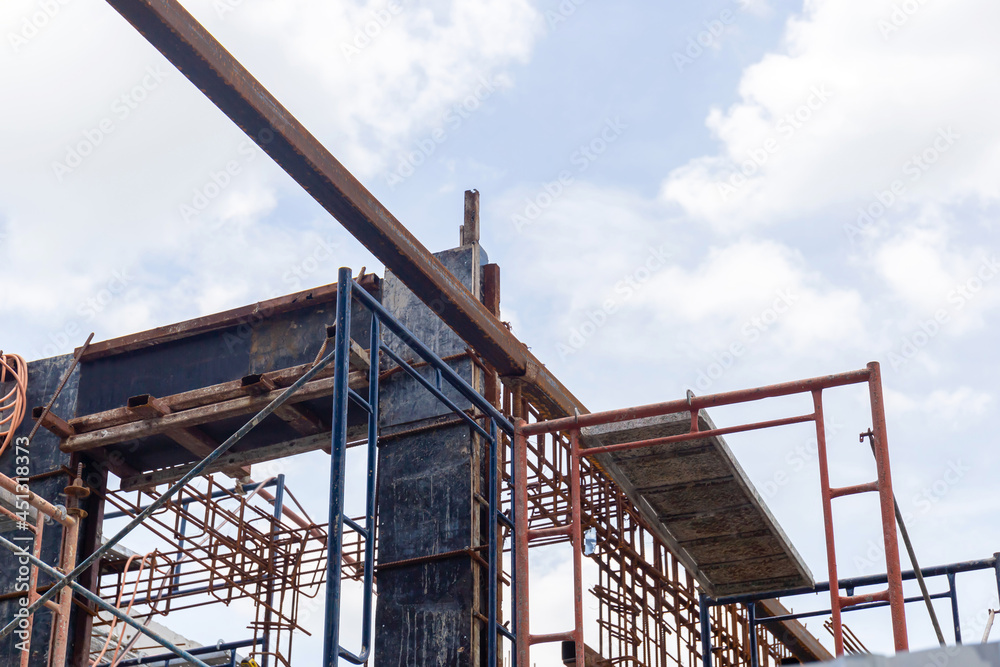 Building and construction site in progress, Beam formwork fabricated by construction worker, pillar and beam being constructed at the construction site against a cloudy sky