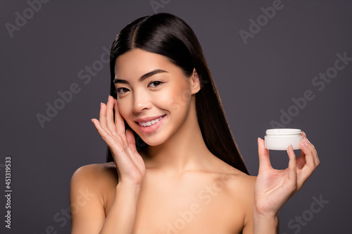 Photo of adorable stunning gorgeous charming sincere lady hold little cream jar apply cheek isolated grey color background