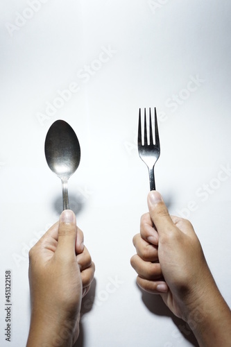hands holding fork and spoon