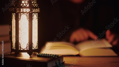 Asian Muslim woman reading the Quran and appreciates and faith The Holy Al Quran with written Arabic calligraphy meaning of Al Quran, Arabic word translation: The Holy Al Quran.