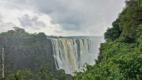 Beautiful Victoria Falls. Powerful streams of water flow into the gorge. Thick fog over the abyss. Lush green vegetation around. Zimbabwe photo