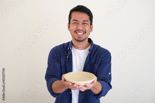 Adult Asian man smiling happy while showing empty eating bowl photo