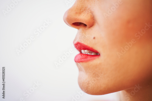 Detail of a woman's lips with red lipstick over white background. Beauty concept
