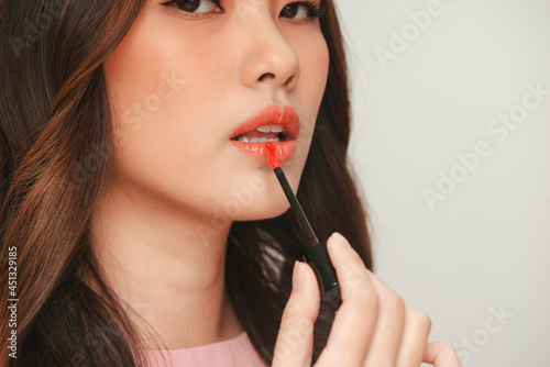 Fototapeta Beautiful Young Woman Apply Moisturizing Lip Gloss