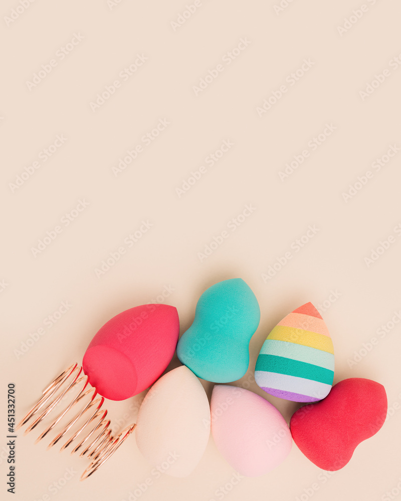 Colorful cosmetic beauty sponges close up different form on beige background with copy space. Top view, flat lay.