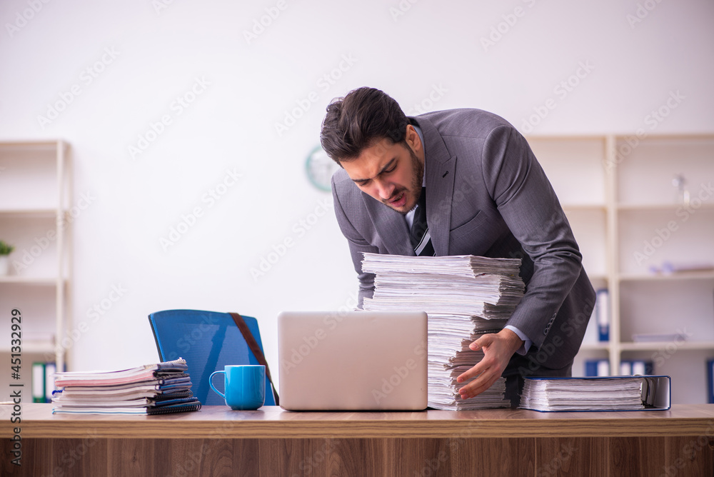 Young businessman employee unhappy with excessive work in the office Young businessman employee unhappy with excessive work in the office