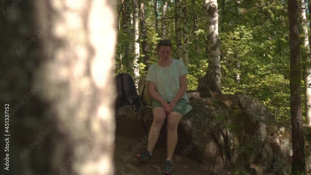 Young Woman Tourist Sits and Resting Among the Green Forest. Next to Her is Backpack. Concept of Hiking and Active Lifestyle. Generation Z New Concept Travels Young Woman Tourist Sits and Resting Among the Green Forest. Next to Her is Backpack. Concept of Hiking and Active Lifestyle. Generation Z New Concept Travels