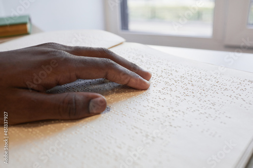 Close up of African-American hand reading braille book for blind, copy space photo