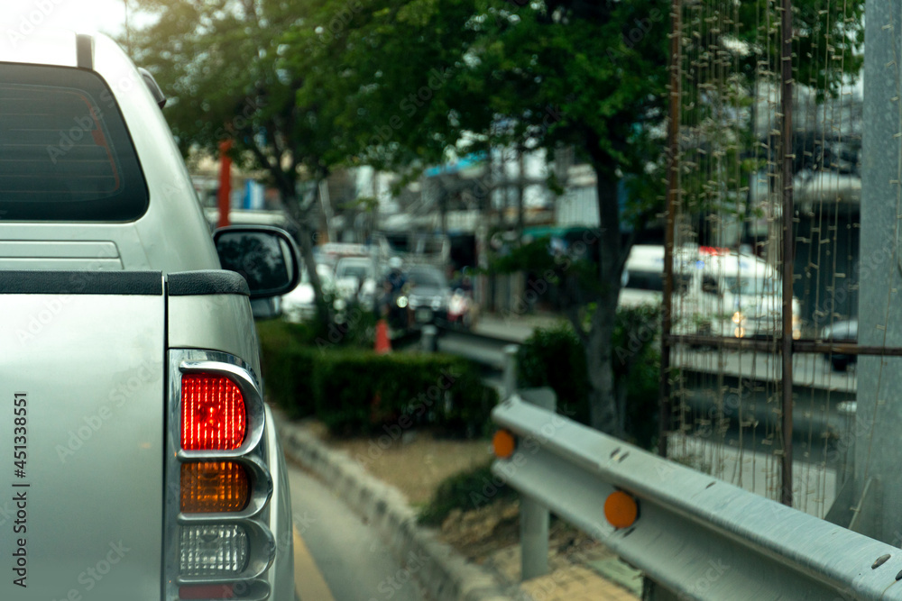 Rear side of pickup white car driving on the asphalt road in the city. During daytime. Several cars across the street ran. with open brake light. Intersection in the middle with trees and roadblocks. Rear side of pickup white car driving on the asphalt road in the city. During daytime. Several cars across the street ran. with open brake light. Intersection in the middle with trees and roadblocks.