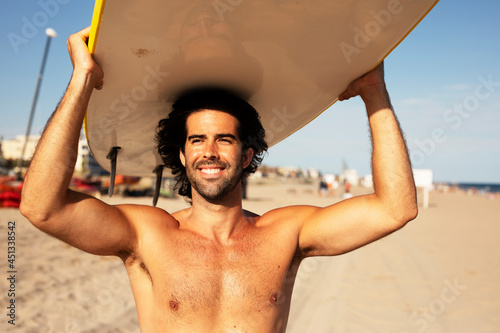 Handsome man with surfboard. Surfer taking a break on the beach.