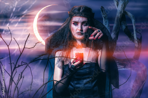 Evil witch with candle in forest at night
