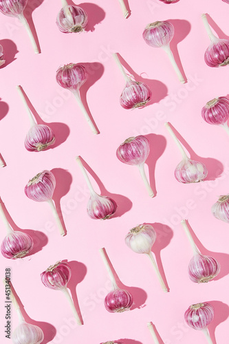 Bulbs of garlic on a colored background, colorful garlic pattern. Garlic pattern on pink background