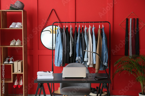 Interior of room with modern workplace and stylish female clothes