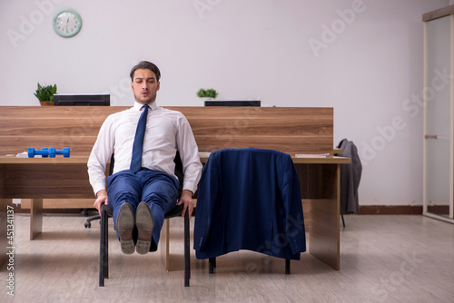 Young businessman employee doing sport exercises at workplace