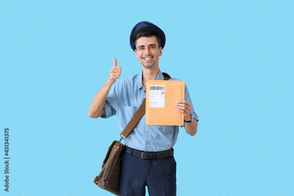 Handsome young postman with letter showing thumb-up on color background Handsome young postman with letter showing thumb-up on color background