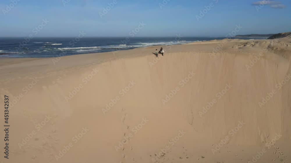 Woman and her son sitting on edge of dune Woman and her son sitting on edge of dune