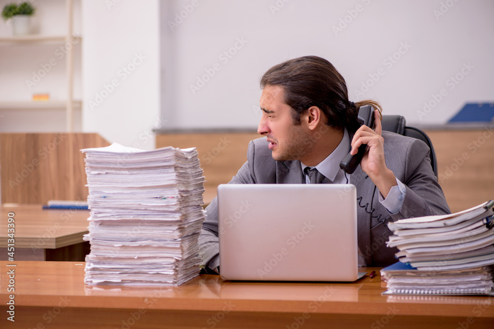 Young male employee and too much work in the office Young male employee and too much work in the office