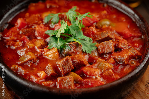 Georgian veal chashushuli stew with tomatoes on a wooden background