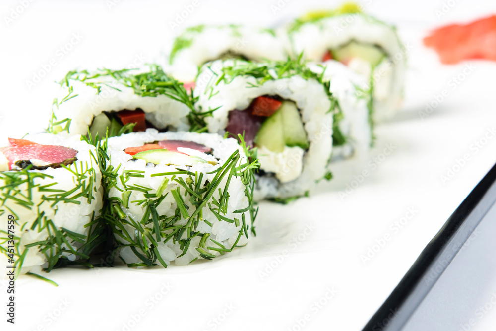 Sushi rolls with tuna, cucumber and cream-cheese in chopped dill. Served on a white plate over white background. Sushi rolls with tuna, cucumber and cream-cheese in chopped dill. Served on a white plate over white background.