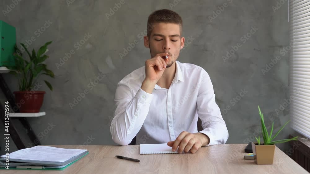 Lifestyle concept. A handsome guy sits in a white shirt at the table and lights a cigarette. nicotine addiction concept. Lifestyle concept. A handsome guy sits in a white shirt at the table and lights a cigarette. nicotine addiction concept.