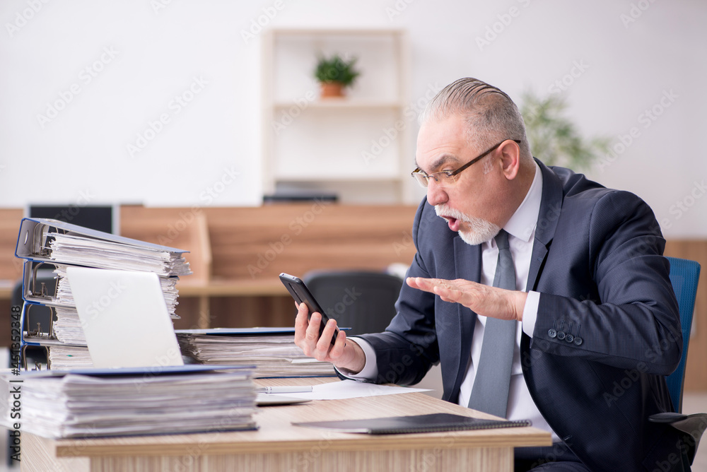 Aged male employee sitting at workplace Aged male employee sitting at workplace